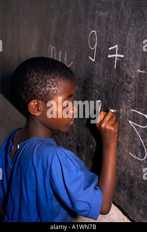 RWANDA KIGALI ÉCOLE PRIMAIRE.Jeune fille écrit sur le tableau noir avec la craie. 1995 Banque D'Images