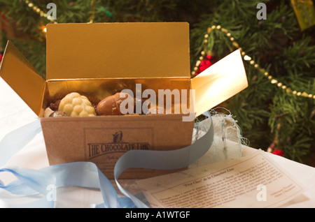 Une boîte ouverte d'un assortiment de chocolats belges faits main en face d'un arbre de Noël décoré Banque D'Images