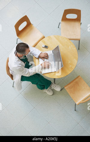 Médecin à l'aide d'ordinateur portable dans une cafétéria, vue de dessus Banque D'Images
