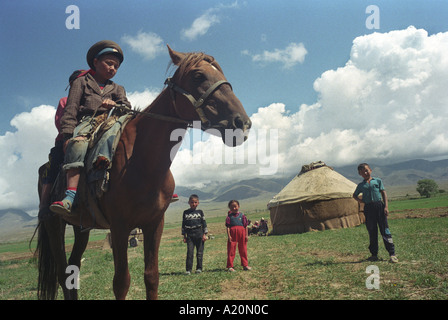 Deux enfants sur un cheval devant leurs familles, la yourte, près du lac Issyk Kul, Kirghizistan Banque D'Images