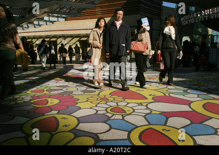 Couple sur un tapis de fleurs souriant devant l'entrée de l'Institut Mori Arts Museum à Roppongi Hills, Tokyo, Japon Banque D'Images