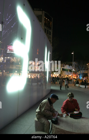La nuit les piétons s'asseoir à côté d'un grand nombre numérique afficher sur le mur de l'immeuble de la télévision TV Asahi à Roppongi Hills Banque D'Images