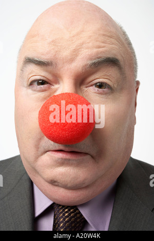 Bald businessman Wearing Clown Nose, fronçant, close-up Banque D'Images