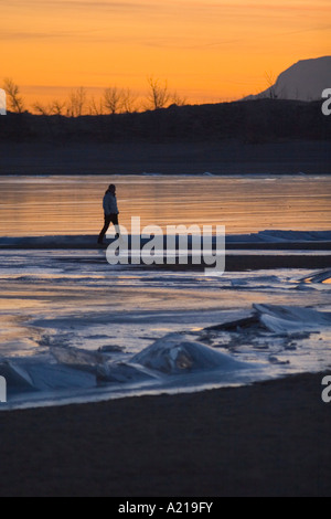 Une femme marche d'un lac gelé au coucher du soleil en hiver près de Huntington l'Utah Banque D'Images