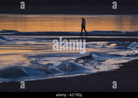 Une femme marche d'un lac gelé au coucher du soleil en hiver près de Huntington l'Utah Banque D'Images