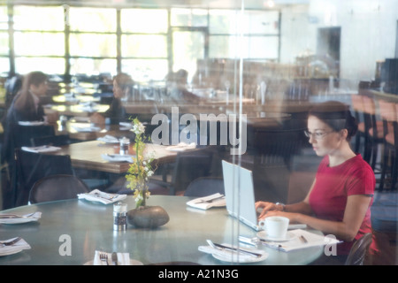 Woman Using Laptop in Restaurant Banque D'Images