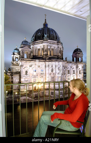 Une femme à la recherche à la Berliner Dom à travers la rivière Spree depuis un balcon de l'hôtel Radisson de Berlin Est. Banque D'Images