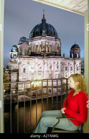 Une femme à la recherche à la Berliner Dom à travers la rivière Spree depuis un balcon de l'hôtel Radisson de Berlin Est. Banque D'Images