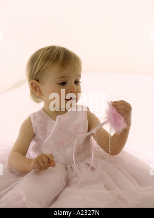 Porter un enfant en robe rose tenant une baguette magique Banque D'Images