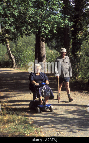 Un utilisateur de fauteuil roulant et son mari sur un chemin à Stover Country Park Newton Abbot Angleterre Banque D'Images