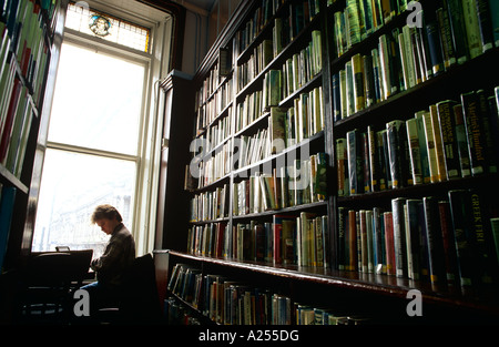 Un lecteur lit à travers les livres dans la Bibliothèque Hall , dans le centre-ville de Belfast en Irlande du Nord Banque D'Images