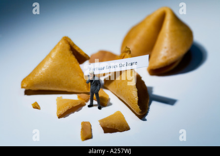 Businessman miniature en face de fortune cookies avec lecture de message la fortune sourit aux audacieux Banque D'Images