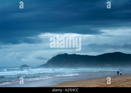 Dark thunder nuages pendre sur le couple walking on beach Banque D'Images