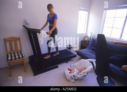 Mère d'exécution sur un tapis roulant dans la chambre avec bébé Banque D'Images