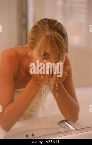 Woman face au lavabo de la salle de bains Banque D'Images