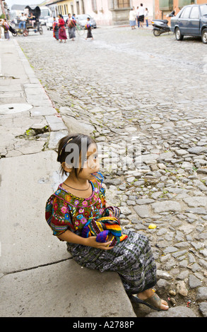 GUATEMALA ANTIGUA belle jeune fille assise Cakchiquel sur la bordure de couleur vive les textiles tissés à la vente Banque D'Images