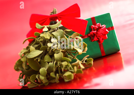 Gui et cadeau de Noël sur fond rouge. Banque D'Images