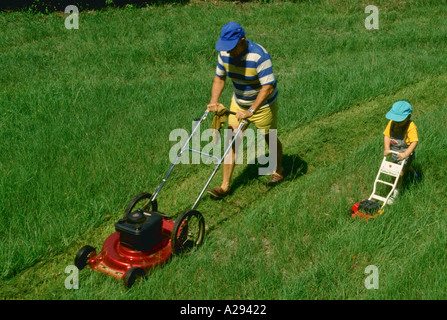 Man and boy le fauchage de l'herbe Banque D'Images