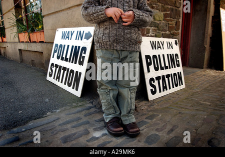 Un jeune enfant debout à l'extérieur de l'entrée du bureau de vote à Chulmleigh, Devon, UK Banque D'Images