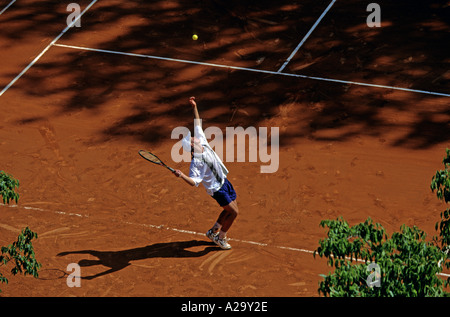 Vue aérienne d'un joueur de tennis masculin de lancer la balle en l'air servant au cours d'un jeu sur une cour d'argile