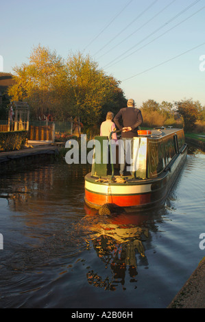 Un couple à bord d'un bateau qui se déplacent le long de l'étroit canal Cauldon dans le Staffordshire en Angleterre. Banque D'Images