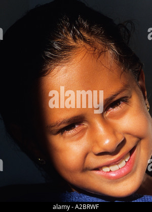 Portrait d'une fille de sept, huit, neuf ans souriant. Ombres.