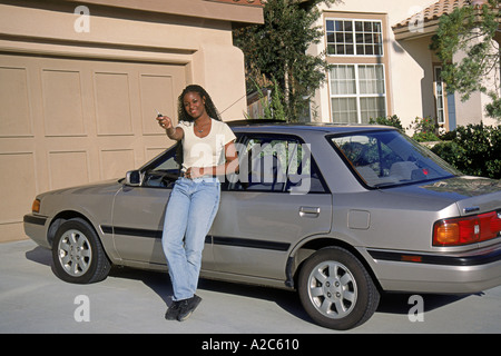 Young African American female teenager standing en voiture dans l'entrée de jour en prouholding Myrleen touches POV MR © Pearson Banque D'Images