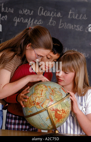 Un groupe de filles de l'école primaire en classe looking at a globe Banque D'Images