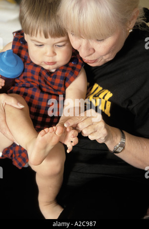 Une grand-mère jouant avec son petit-fils des pieds pendant qu'il est assis sur ses genoux Banque D'Images