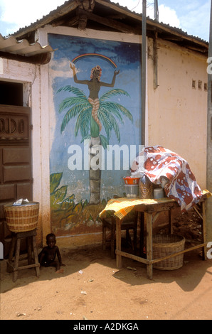 Enfant africain à l'ombre par une peinture murale voodoo, Ouidah, Bénin. Banque D'Images