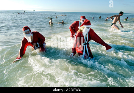 Hardy nageurs habillés en Père Nöel prendre part à la Journée annuelle de Noël à profiter de la mer à Brighton sur un beau matin de Noël Banque D'Images