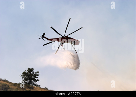 L'eau chute d'hélicoptère Sikorsky sur un feu de forêt avec de la fumée à l'arrière-plan Banque D'Images