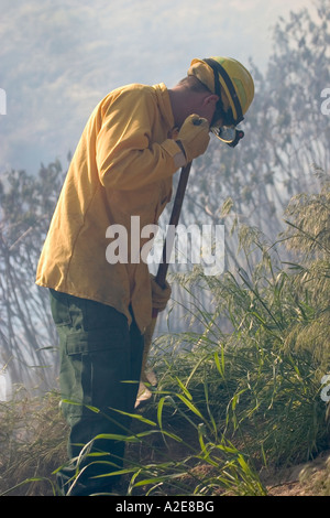 Fireman de creuser une tranchée à un feu de brousse Banque D'Images