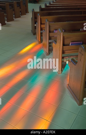 Bancs d'église avec vitrail de lumière qui brille sur le sol faisant un motif coloré à l'Église catholique romaine, USA Banque D'Images