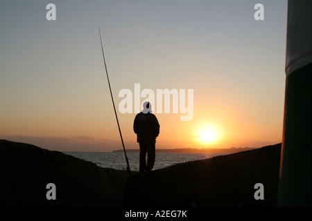 Silhouette pêcheur debout à côté de la plage Alvor dans le soleil du soir Algarve Portugal Banque D'Images