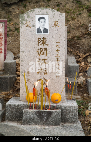 dh Pierre tombale chinois CHEUNG CHAU HONG KONG Joss bâtons et orange offrant la pierre tombale de cimetière dans le tombeau de pierres tombales de cimetière Banque D'Images