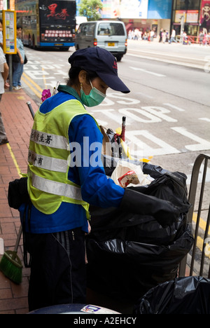 dh CAUSEWAY BAY HONG KONG jeune fille collecteur de poubelle avec masque d'hygiène collecte de poubelle de poussière personnes portant des masques Banque D'Images