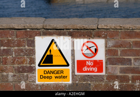 Des pancartes Danger eau profonde et pas de plongée sur un mur sur le côté de Lymington Harbour Banque D'Images