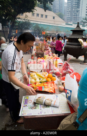 dh Wong Tai Sin Temple WONG TAI SIN HONG KONG Worshipper organisant des cadeaux sur la table des offrandes orange chinois bonne chance Banque D'Images