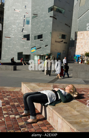 Girl lying in the sun Federation Square Victoria Australie Melbourne CBD Banque D'Images