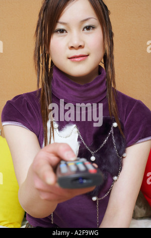 Portrait d'une jeune femme tenant une télécommande Banque D'Images