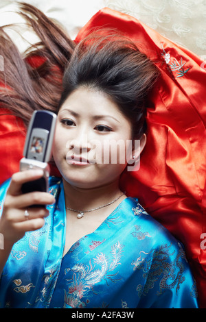 High angle view of a young woman lying on her back holding a mobile phone Banque D'Images