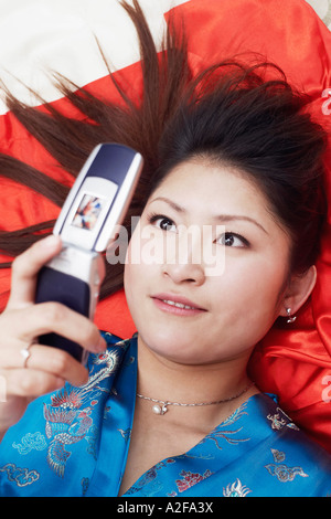 High angle view of a young woman lying on her back holding a mobile phone Banque D'Images