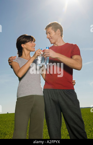 Jeune couple toasting with water bottle, smiling Banque D'Images