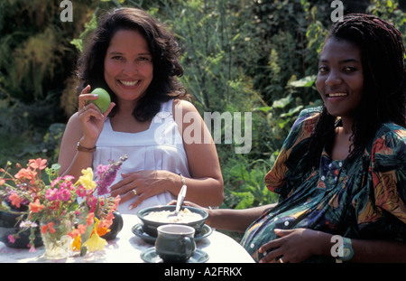 Noir portrait femme enceinte bénéficiant d'un brunch avec Hispanic woman in garden Banque D'Images