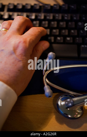 Main de l'homme médecin sur le clavier de l'ordinateur avec stéthoscope Banque D'Images