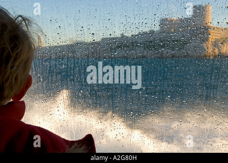 342 un portrait Portrait d'un jeune garçon sur le ferry à travers une fenêtre couverte de gouttelettes d'eau Banque D'Images