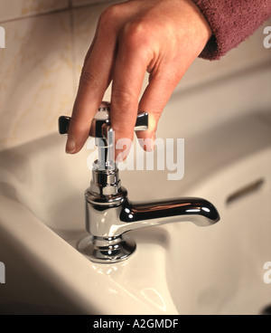 Une main de femme est titulaire d'un robinet de bain chrome prêt à tourner sur l'eau Banque D'Images
