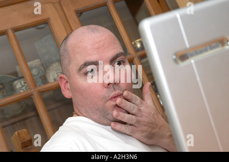 Homme regardant choqués par ce qu'il voit sur l'écran de l'ordinateur portable Banque D'Images
