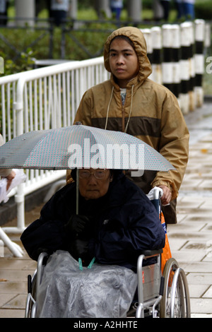 Filipino Amah, marcher avec une personnes âgées employeur dans le parc Victoria, Hong Kong SAR Banque D'Images